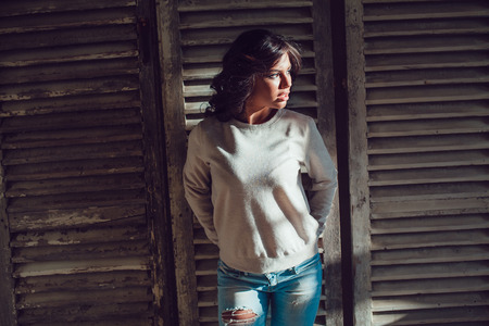 Beautiful young womanl dressed in blank sweatshirt standing on wood wall background. Mock-up.の写真素材
