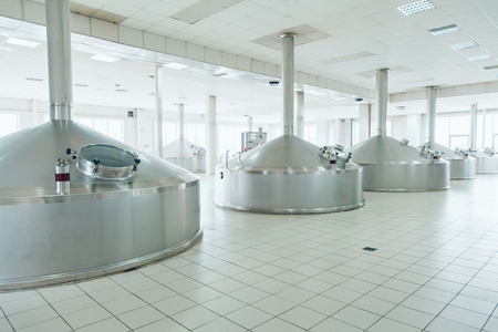 Brewing production - metal beer tanksin a spacious hall. Brewery.