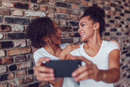 Two attractive African girls make selfie at home.の写真素材