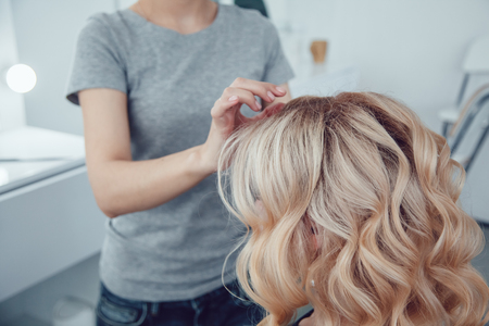 Hair stylist makes a curls for a girl, using hair styling. Hairdresser at work.の写真素材