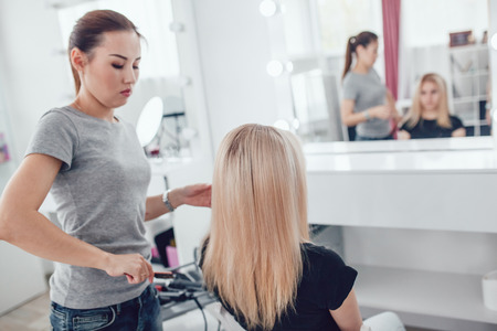 Hair-stylist by hair combs girl hair in beauty studio.の写真素材