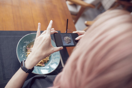 Attractive woman makes a photo of a carbonara paste in a cafe.の写真素材
