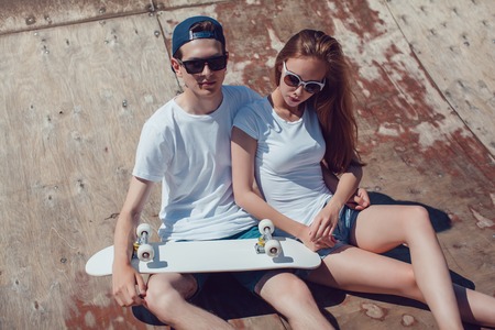 Young skater boy and girl with skateboard posing in skate park. Mock up.