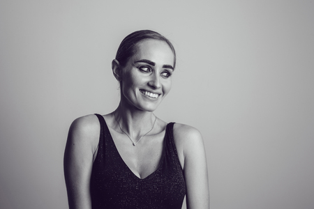 Beautiful woman in black night fashion dress posing on a gray background.の写真素材