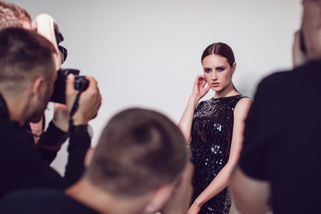 Photographers paparazzi take photos of woman in cocktail dresses.の写真素材