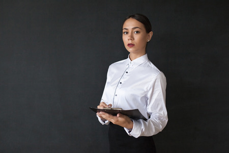 Business woman holding documents standing on dark background.の写真素材