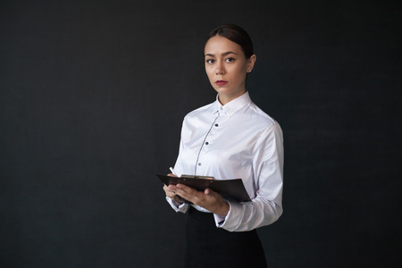 Business woman holding documents standing on dark background.の写真素材