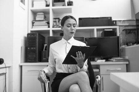 Business woman sitting in office and examining documents.の写真素材