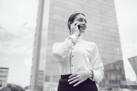 Business woman stands on the background of business center and makes calls.の写真素材