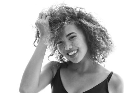 Portrait of a curly woman with freckles and naked shoulders.