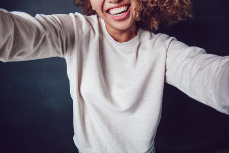 Curly haired girl with freckles in blank grey sweatshirt on dark background. Mock up.の写真素材