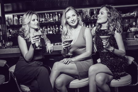 Beautiful women are sitting on the bar and drinking cocktails.