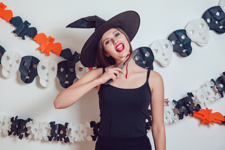 Woman in a witch's suit holds a knife at her throat. Halooween.の写真素材