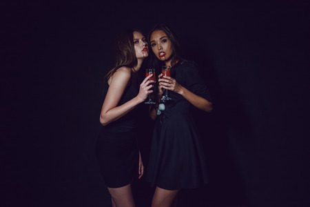 Attractive girls in the image of vampires hold glasses with blood. Halloween.の写真素材