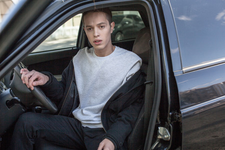 Young man in gray sweatshirt in car. Mock-up.の写真素材