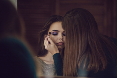 Make-up artist doing makeup to girl in studio.の写真素材