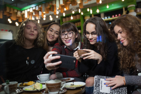Group of positive teenagers make selfies and spending time in a cafe.の写真素材