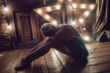 Beautiful blonde woman is sitting on the wooden floor.の写真素材
