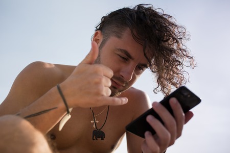 A man with curly hair uses a smartphone.の写真素材