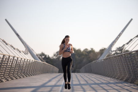 Active woman runner jogging across bridge, outdoors running, sport and healthy lifestyle concept.の写真素材