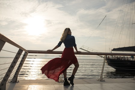 Beautiful woman in red dress on the background of the sea.