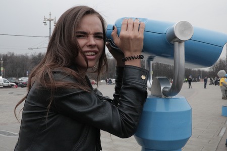 Young woman looks at the city through binoculars.