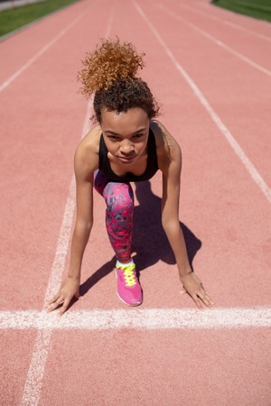 Confident young sportswoman getting ready to run a distance on the track.の写真素材