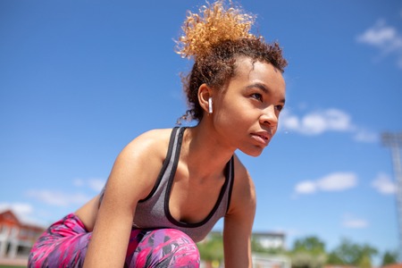 Confident young sportswoman getting ready to run a distance at the stadium.の写真素材