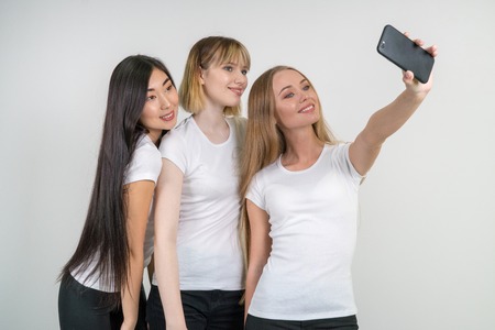 Beautiful funny girls make selfie. Girls in white T-shirts.の写真素材