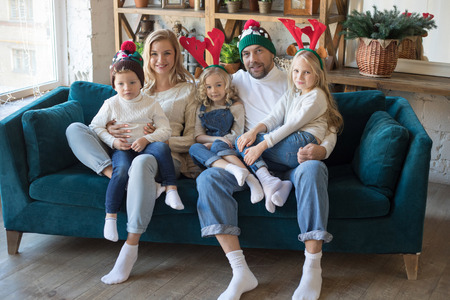 Happy family in funny Christmas hats sitting on the sofa.