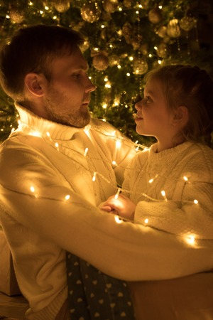 Dad and daughter fool around the Christmas tree.の写真素材