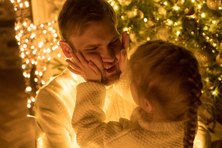 Dad and daughter fool around the Christmas tree.