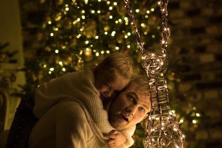Girl sitting on her fathers back near the christmas tree.の写真素材