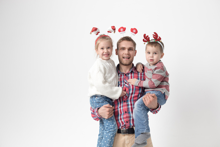 Father holds children in his arms on a white background. Happy family in funny Christmas headbands.の写真素材