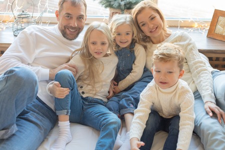 Friendly family of five people sitting on the bed.の写真素材
