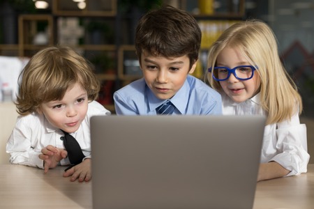 Little children businessmen work in the office and use a laptop.