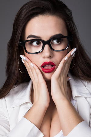 Portrait of a sexy brunette woman in glasses with a surprised expression.の写真素材