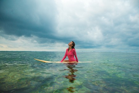 Beautiful woman swims on a surfboard.