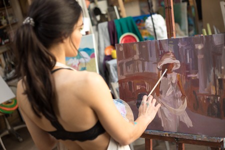 Professional Woman artist painting picture in art studio.