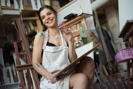 Professional Woman artist painting picture in art studio.の写真素材