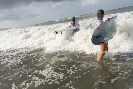 Surfer women in white t-shirt go to the ocean with boards.の写真素材