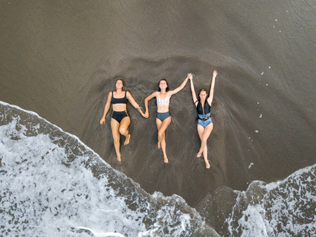 Top view of a women lying on the beach with black sand, foaming waves of ocean.の写真素材