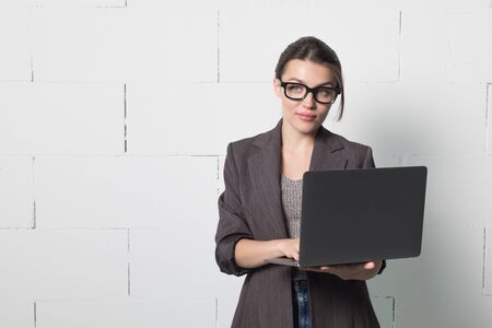 Business woman in glasses and suit with a laptop in hand on white background.の写真素材