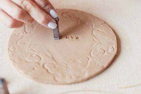 Hands make a round clay product with the words Family.