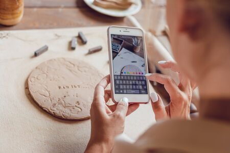 Woman makes a photo of her work from clay with the words "family".の写真素材