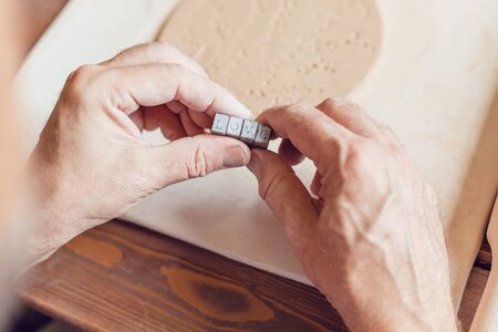 Hands make a round clay product with the words "love".の写真素材