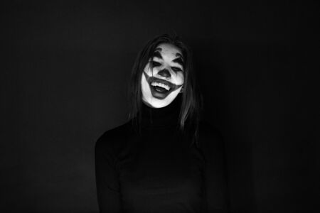 KAZAKHSTAN, KOSTANAY - OCTOBER 21, 2019: Girl with a joker makeup laughs insanely on the dark background.のeditorial素材