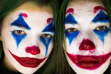 Portrait of two young women with clown makeup on black background.のeditorial素材