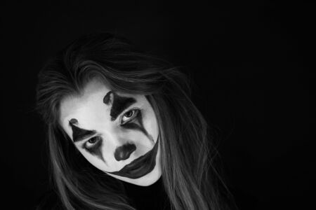 Portrait of a girl with clown makeup on a black background.のeditorial素材