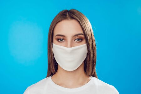 Woman wearing face protective mask on face against Coronavirus on the blue background.